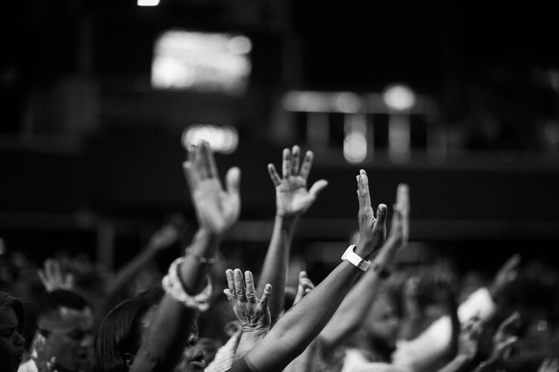 Photo of people raising hands up in the air together.